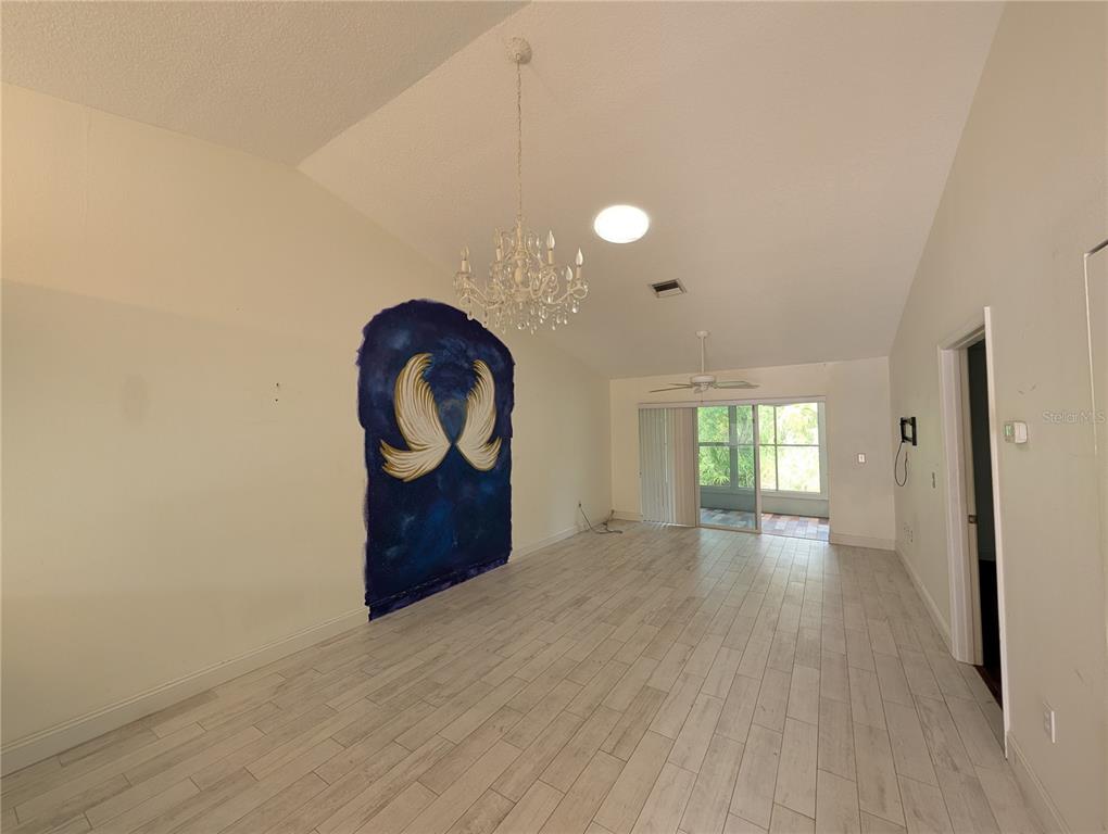 A dining room with light wood-look tile floors, a crystal chandelier, and a painted mural — 638 N JEFFERSON AVENUE UNIT 15, SARASOTA, FL