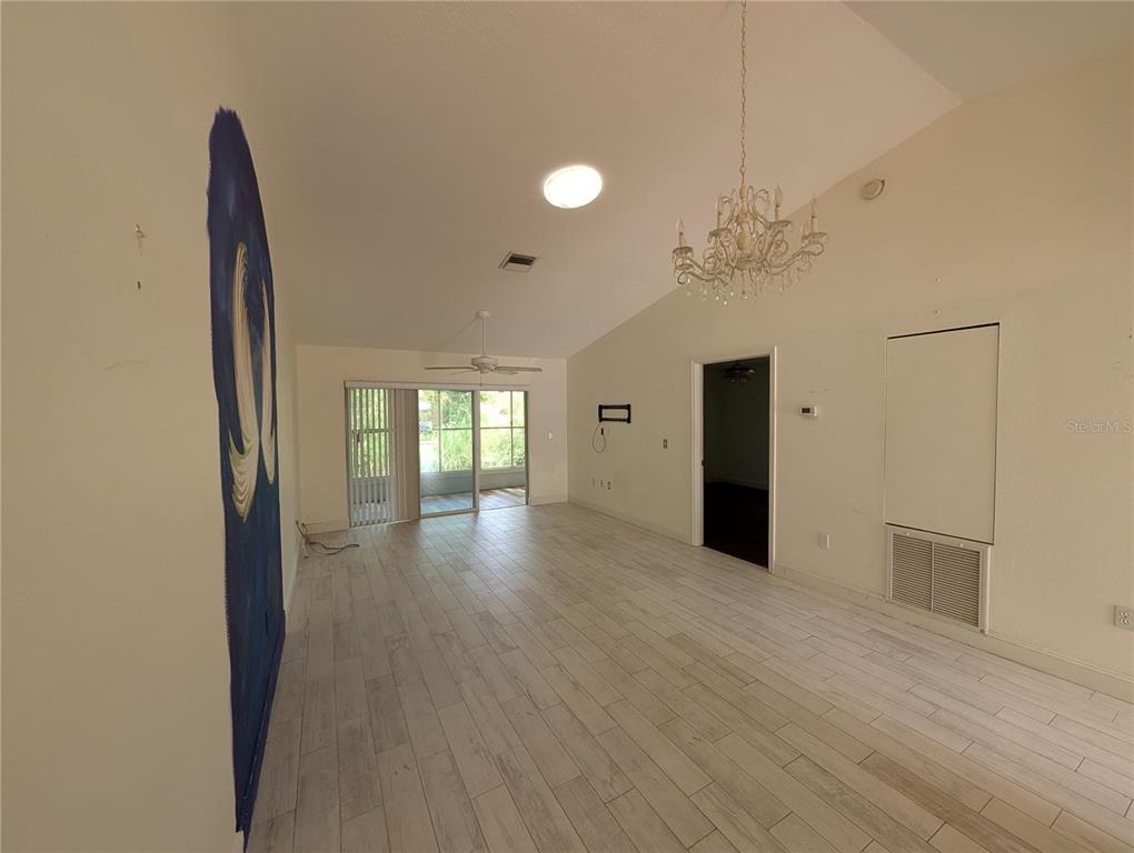 A living room with vaulted ceilings, a chandelier, light-colored tile flooring, and a sliding door — 638 N JEFFERSON AVENUE UNIT 15, SARASOTA, FL