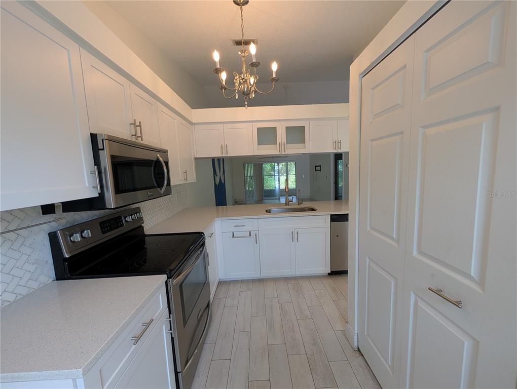 A kitchen features white cabinets, stainless steel appliances, a chandelier, and light-colored tile flooring — 638 N JEFFERSON AVENUE UNIT 15, SARASOTA, FL