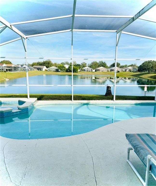 A screened-in pool and spa overlook a lake surrounded by houses — 1144 CLEAR CREEK CIRCLE, CLERMONT, FL