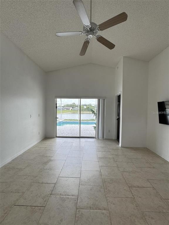 A bright living room with tile flooring, a ceiling fan, and sliding doors to a pool — 1144 CLEAR CREEK CIRCLE, CLERMONT, FL