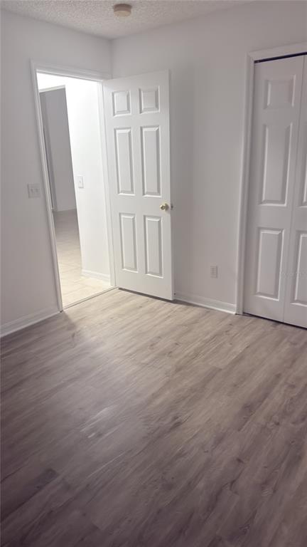 An interior view of a room with wood-look flooring, a white door, and a closet — 1144 CLEAR CREEK CIRCLE, CLERMONT, FL