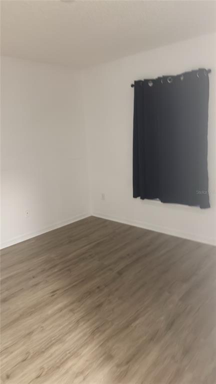 An empty room features white walls, light wood-look flooring, and dark curtains over a window — 1144 CLEAR CREEK CIRCLE, CLERMONT, FL