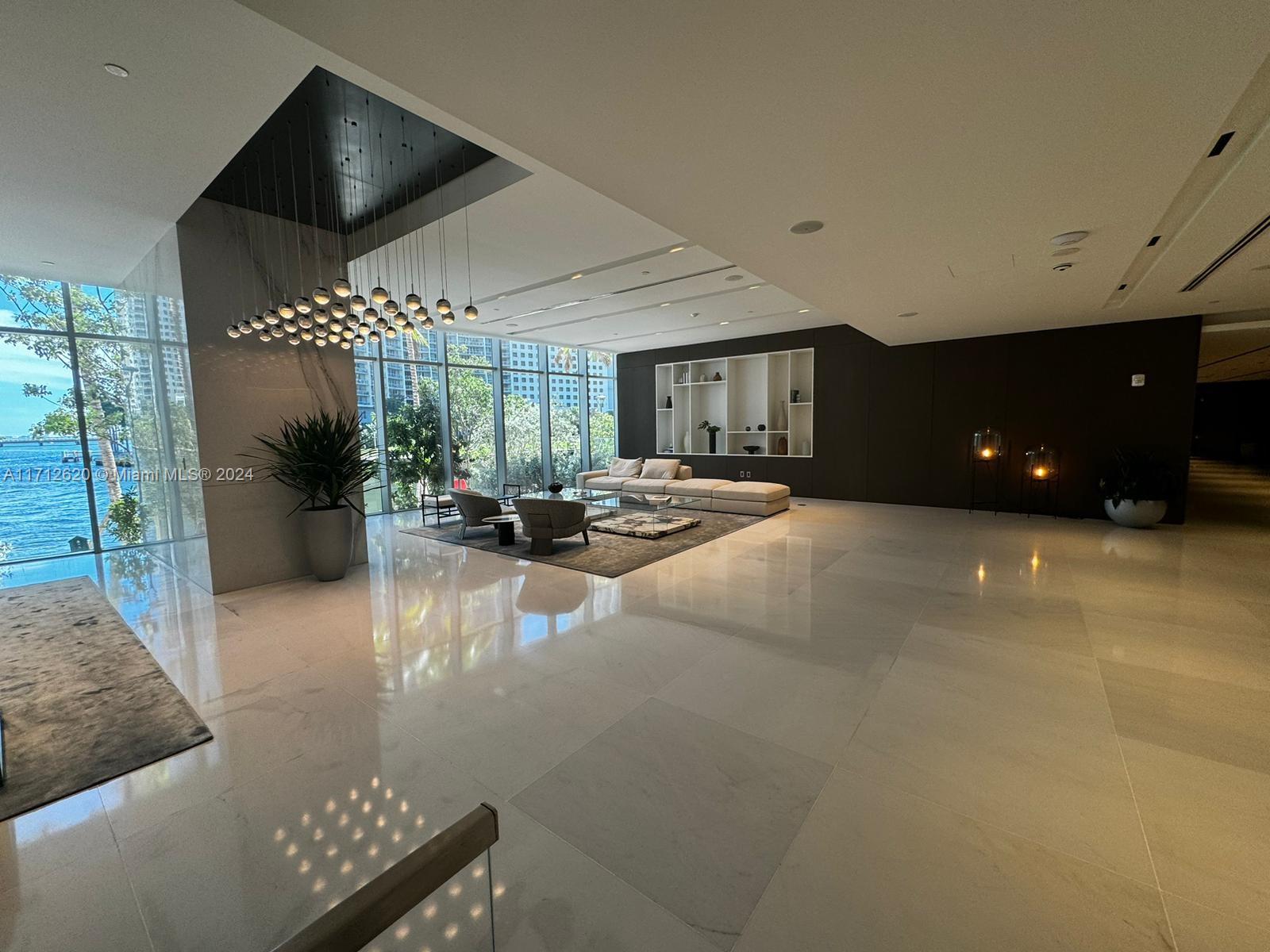 A spacious, modern lobby features marble floors, a large chandelier, and floor-to-ceiling windows overlooking water — 300 Biscayne Boulevard Way # 1806, Miami FL 33131, MIAMI, FL