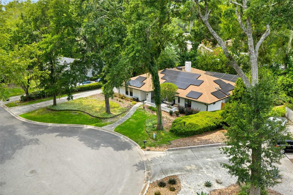 An aerial view shows a single-story house with solar panels on a shingled roof — 2322 NW 14TH PLACE, GAINESVILLE, FL