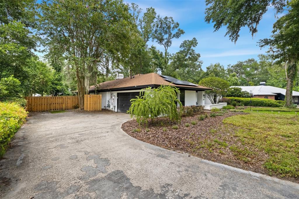 A white brick house with a dark garage door, brown roof, and a concrete driveway — 2322 NW 14TH PLACE, GAINESVILLE, FL