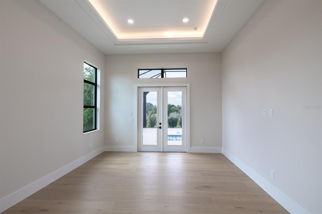 A bright room with light wood floors, a tray ceiling, and double glass doors — 200 BLUE PEARL CT., SARASOTA, FL