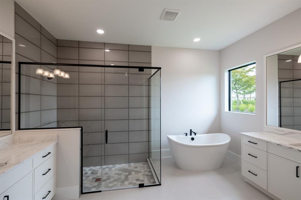A modern bathroom features a glass-enclosed shower, a freestanding tub, and white double vanities — 200 BLUE PEARL CT., SARASOTA, FL