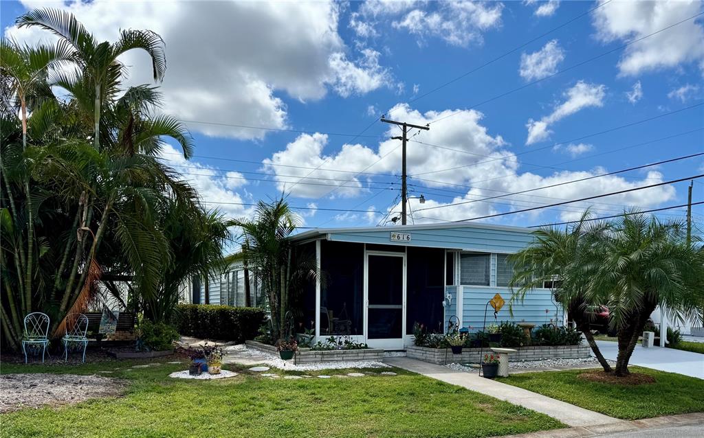A light blue mobile home with a screened-in porch and palm trees in the front yard — 616 50TH AVENUE TERRACE W, BRADENTON, FL