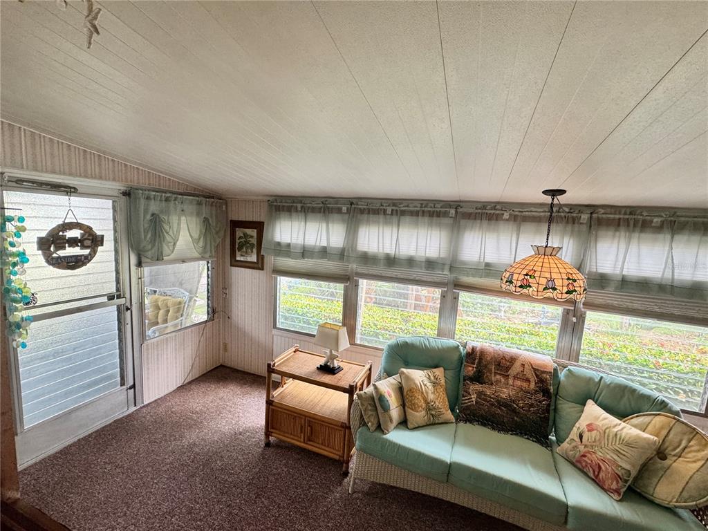A sunroom features a light blue sofa, a wicker side table, and large windows — 616 50TH AVENUE TERRACE W, BRADENTON, FL