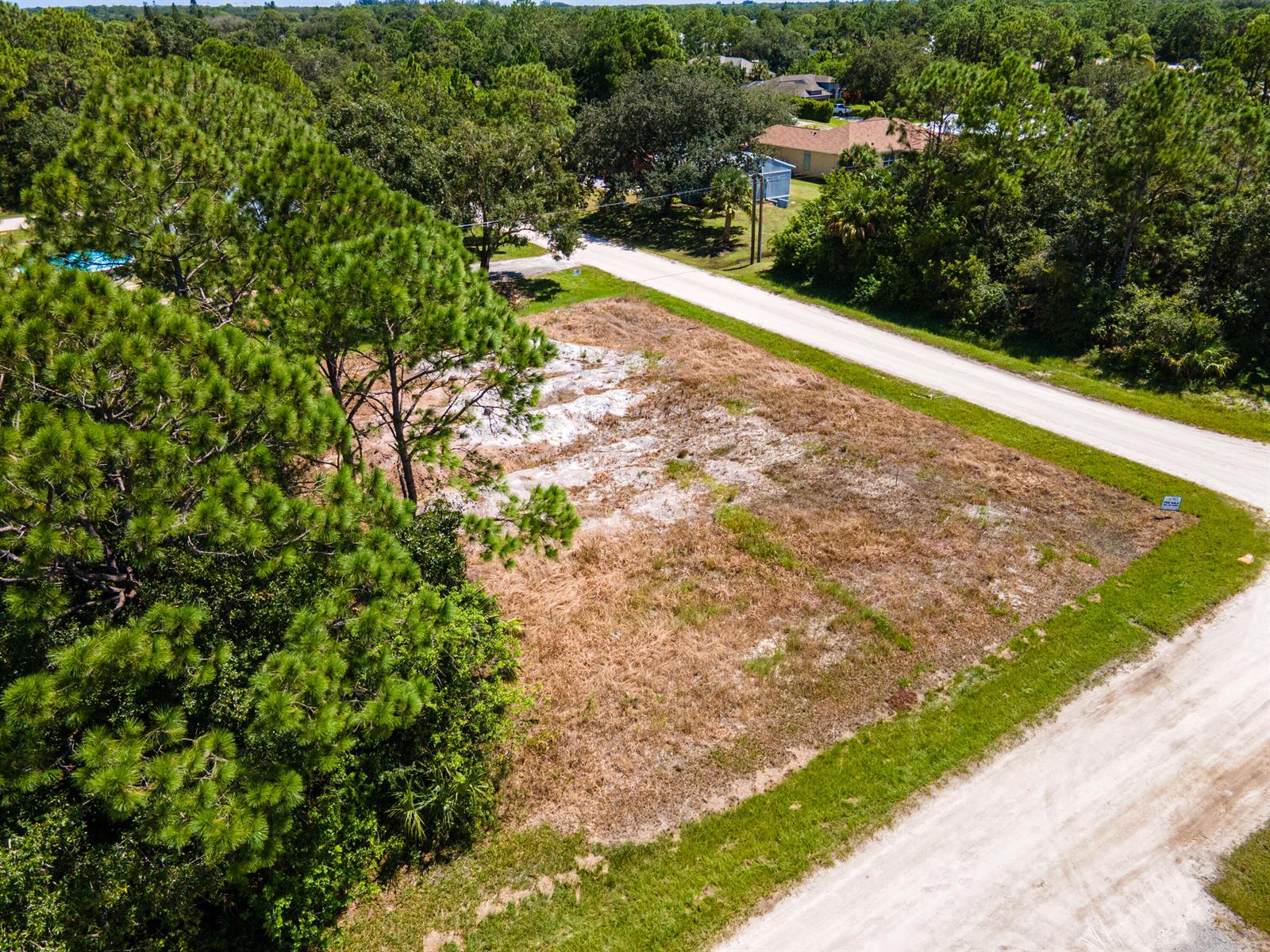 An aerial view shows a vacant, grassy lot bordered by dirt roads and pine trees — 9216 103rd Court, Vero Beach FL 32967, VERO BEACH, FL