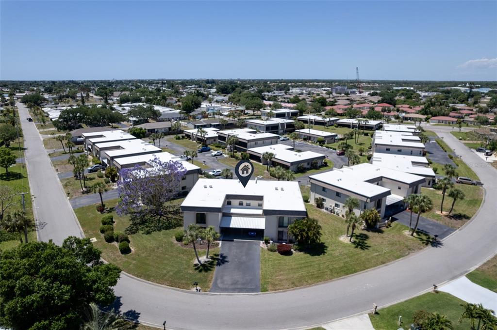 An aerial view shows a multi-unit residential complex with flat roofs and surrounding green lawns — 1727 BONITAS CIRCLES UNIT 1718-C, VENICE, FL