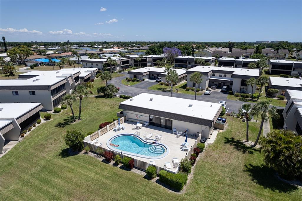 An aerial view shows a community swimming pool surrounded by a fence and apartment buildings — 1727 BONITAS CIRCLES UNIT 1718-C, VENICE, FL