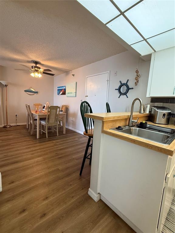 A kitchen with a wooden countertop and sink overlooks a dining area with wood flooring — 3006 CARING WAY UNIT 409, PORT CHARLOTTE, FL