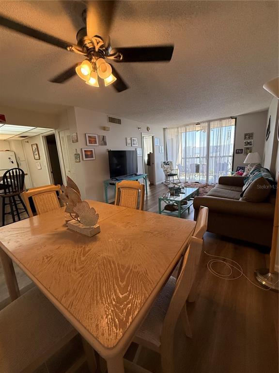 A dining area with a wooden table sits in the foreground of a living room — 3006 CARING WAY UNIT 409, PORT CHARLOTTE, FL