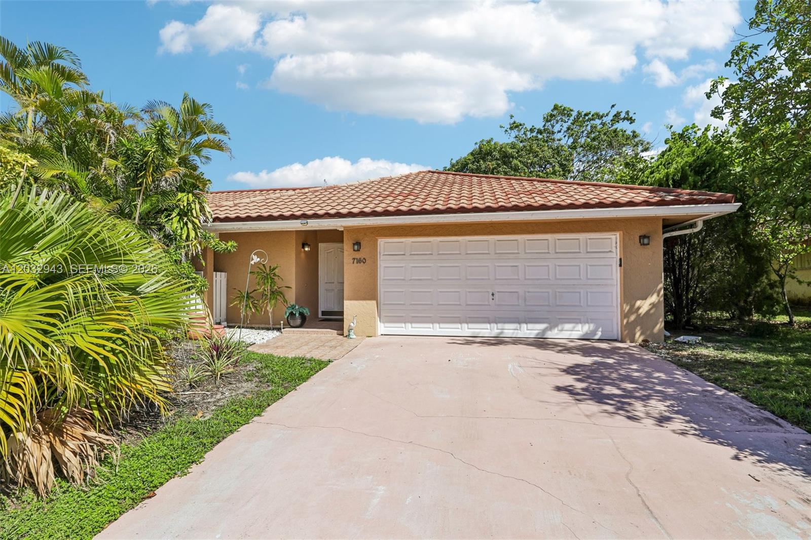 A single-story house with a tan stucco exterior, a tiled roof, and a white garage door — 7160 NW 4th Ave, Boca Raton FL 33487, BOCA RATON, FL