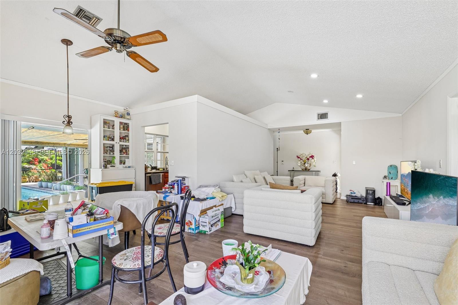 A living and dining area features white furniture, wood-look flooring, and a view of a pool — 7160 NW 4th Ave, Boca Raton FL 33487, BOCA RATON, FL