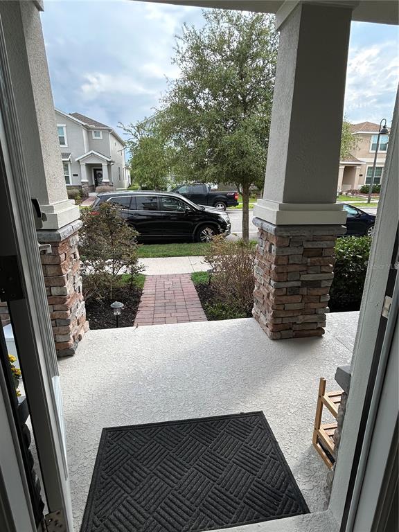 A view from a doorway looking out onto a covered porch with stone-based pillars — 11831 CHARADES STREET, ORLANDO, FL