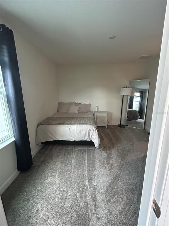 A bedroom features a bed, a nightstand, a floor lamp, and a full-length mirror — 11831 CHARADES STREET, ORLANDO, FL