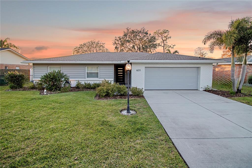 A single-story house with a gray exterior, a two-car garage, and a front lawn — 601 LAKE PANSY DRIVE NW, WINTER HAVEN, FL