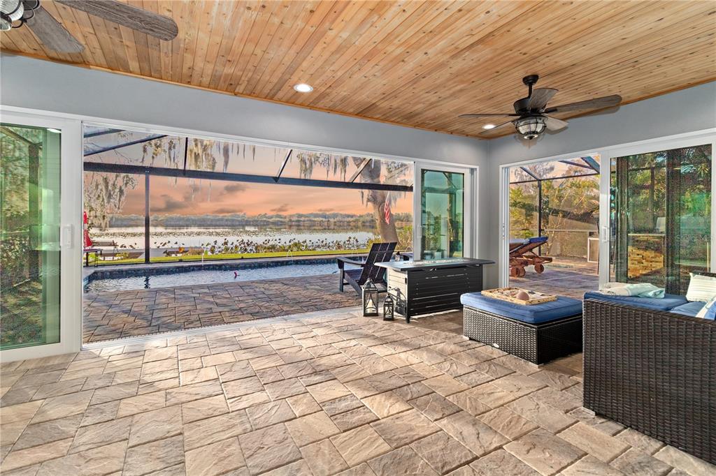 A covered patio with a wood-plank ceiling overlooks a swimming pool and a lake — 601 LAKE PANSY DRIVE NW, WINTER HAVEN, FL