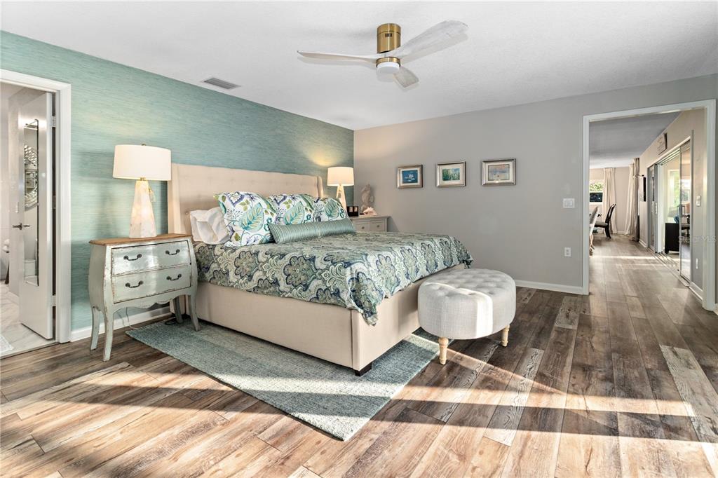 A bedroom features a king bed, teal accent wall, wood-look flooring, and a ceiling fan — 601 LAKE PANSY DRIVE NW, WINTER HAVEN, FL