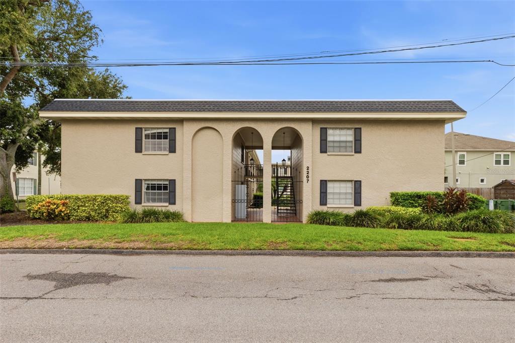 A two-story tan apartment building features arched entryways and a central metal staircase — 2207 S CAROLINA AVENUE UNIT 9, TAMPA, FL