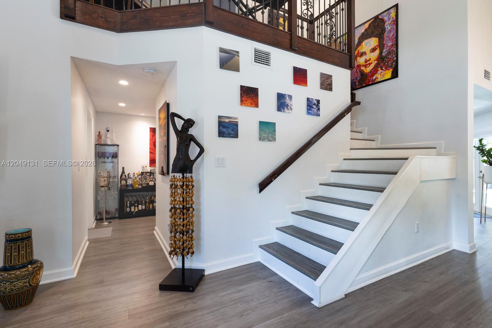 A foyer features a staircase with dark wood treads, a bar area, and wall art — 11035 NW 47th Ln, Doral FL 33178, DORAL, FL