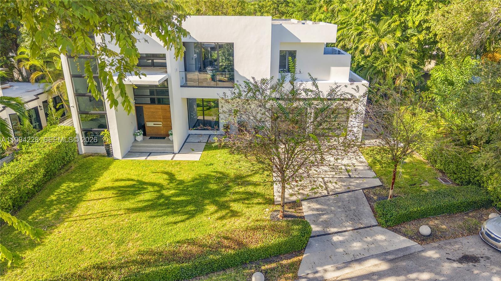 An aerial view shows a modern white two-story house with a driveway and lawn — 3764 Carmen Ct, Miami FL 33133, MIAMI, FL