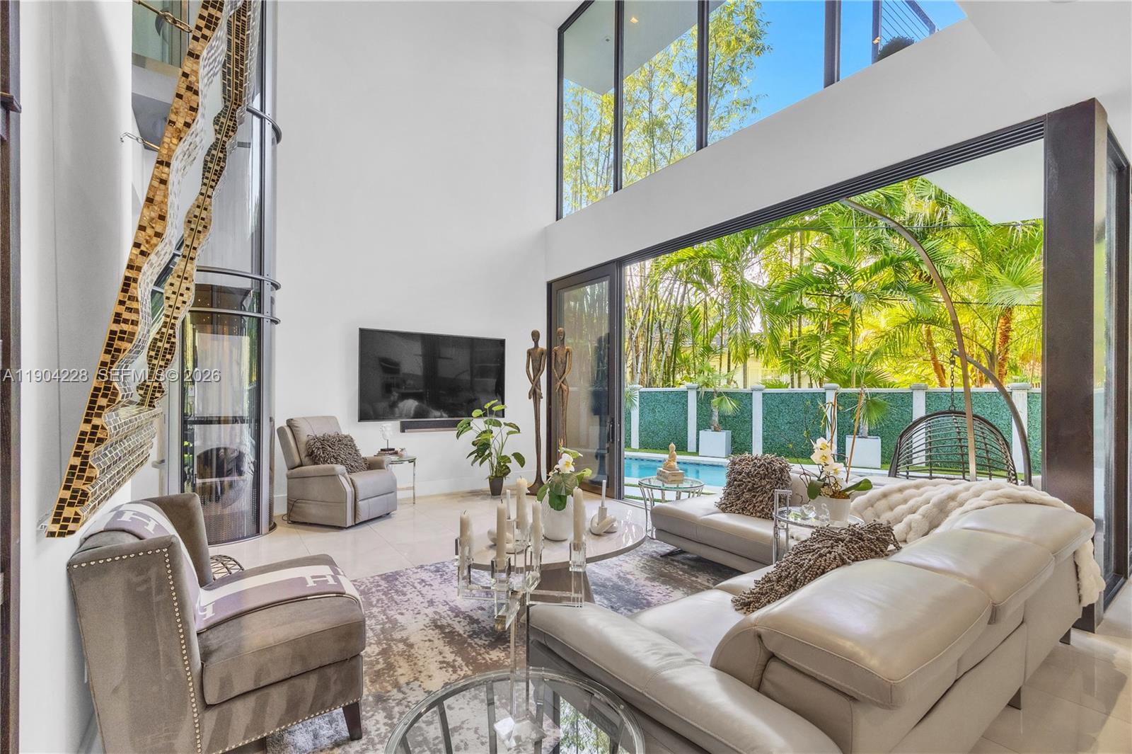 A modern living room with double-height ceilings, floor-to-ceiling windows, and a view of a pool — 3764 Carmen Ct, Miami FL 33133, MIAMI, FL