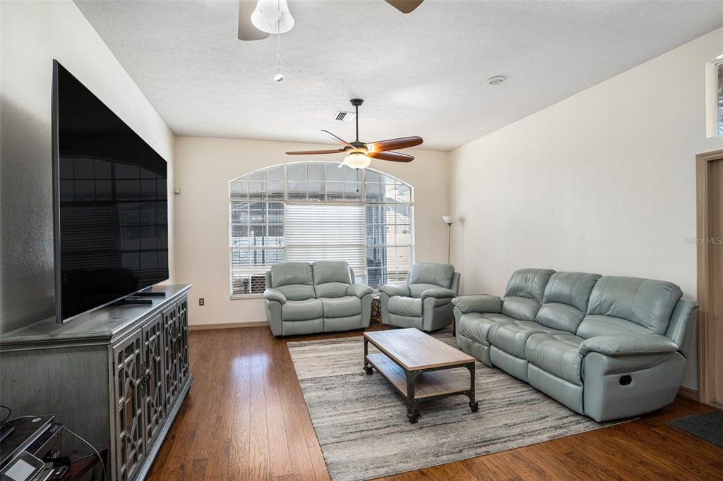 A living room features light blue leather furniture, a wooden coffee table, and hardwood floors — 7741 DAMASK LANE, NEW PORT RICHEY, FL