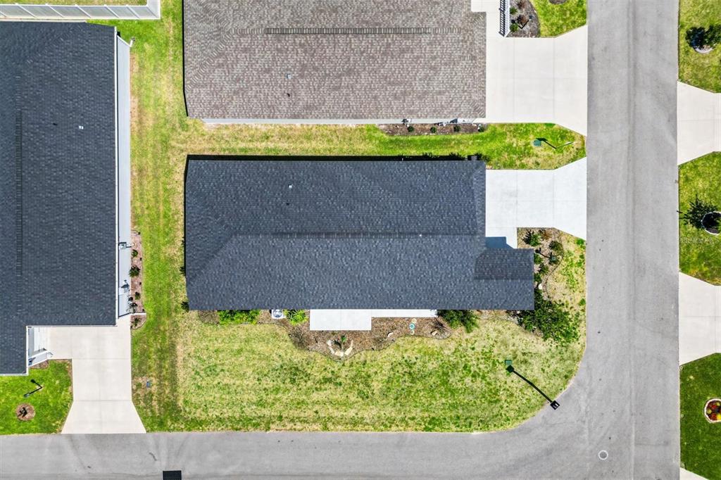 An aerial view shows a residential house with a dark roof and surrounding lawn — 1599 OLIVIA TERRACE, THE VILLAGES, FL