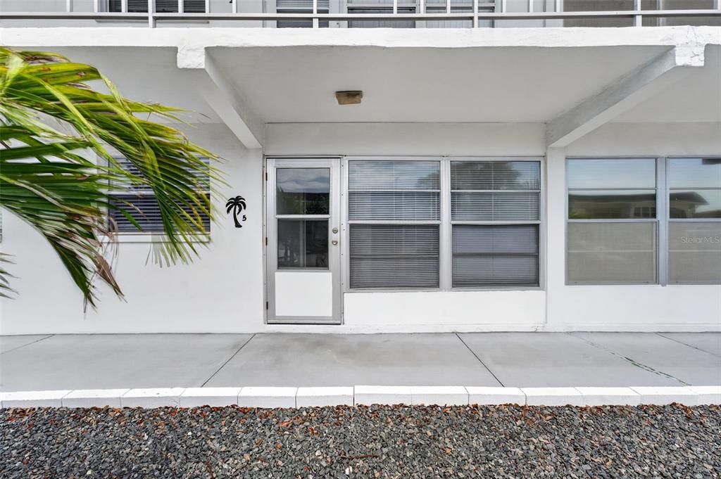 The exterior view shows a white building facade with a glass door and windows — 1221 DREW STREET UNIT A5, CLEARWATER, FL