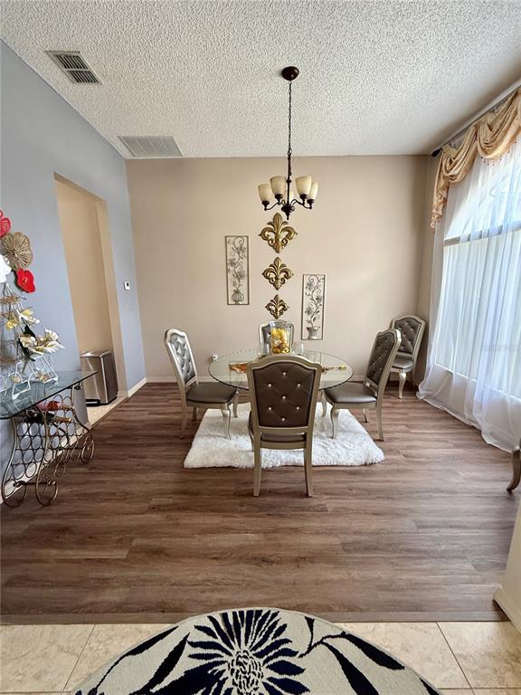 A dining room features a glass table, four tufted chairs, and a chandelier on wood flooring — 1748 FLORENCE VISTA BOULEVARD, ORLANDO, FL