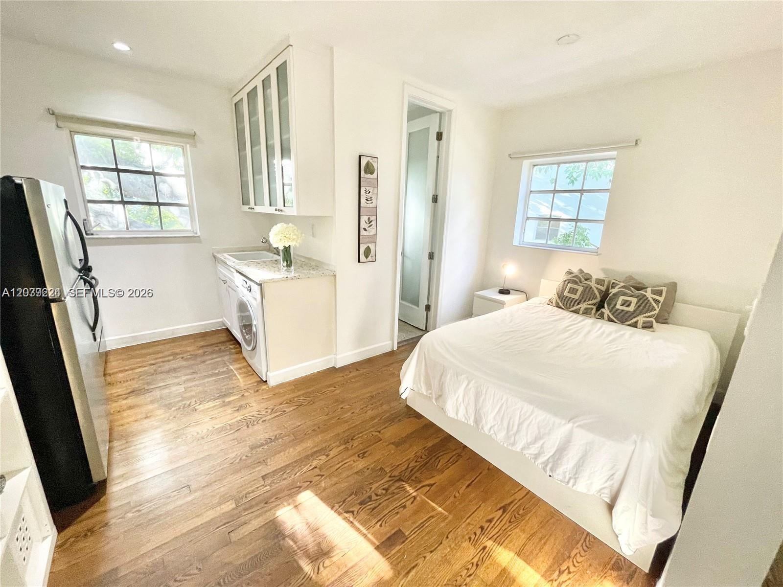 A studio apartment features a kitchenette with a washer, hardwood floors, and a bed — 439 15th St # 18, Miami Beach FL 33139, MIAMI BEACH, FL
