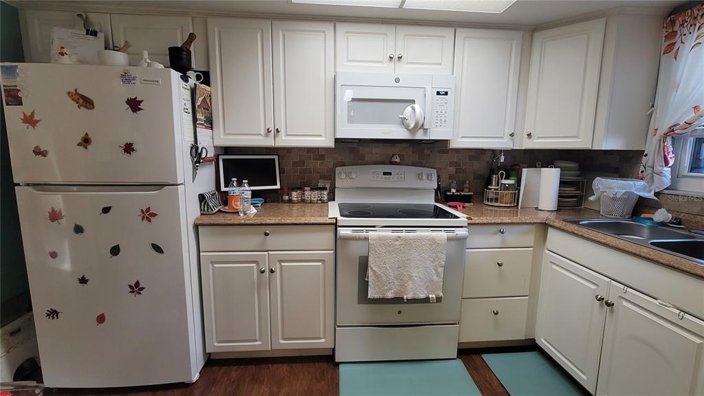 A kitchen features white cabinets, a white refrigerator, a stove, and a microwave — 4924 LIVE OAK CIRCLE UNIT 115, BRADENTON, FL