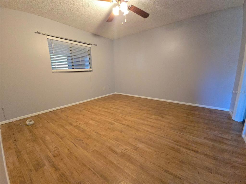 An empty bedroom features light gray walls, wood-look flooring, and a ceiling fan — 4924 LIVE OAK CIRCLE UNIT 115, BRADENTON, FL