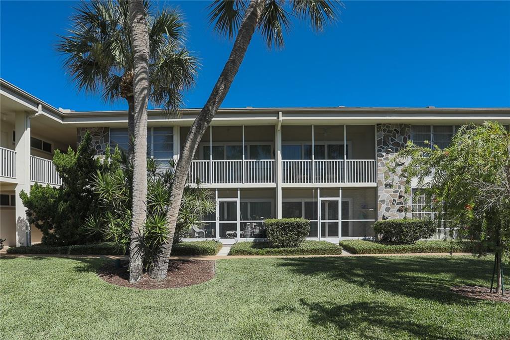 A two-story apartment building features screened balconies, stone accents, and a landscaped lawn with palms — 500 S WASHINGTON DRIVE UNIT 16A, SARASOTA, FL