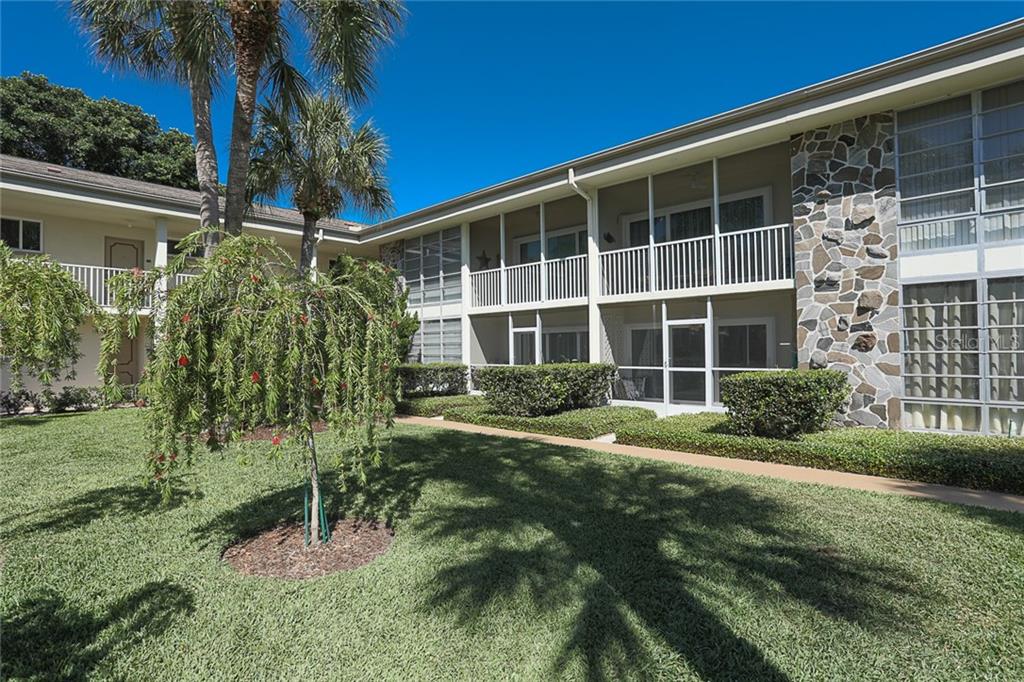 A two-story apartment building with screened balconies, stone accents, and a landscaped lawn — 500 S WASHINGTON DRIVE UNIT 16A, SARASOTA, FL