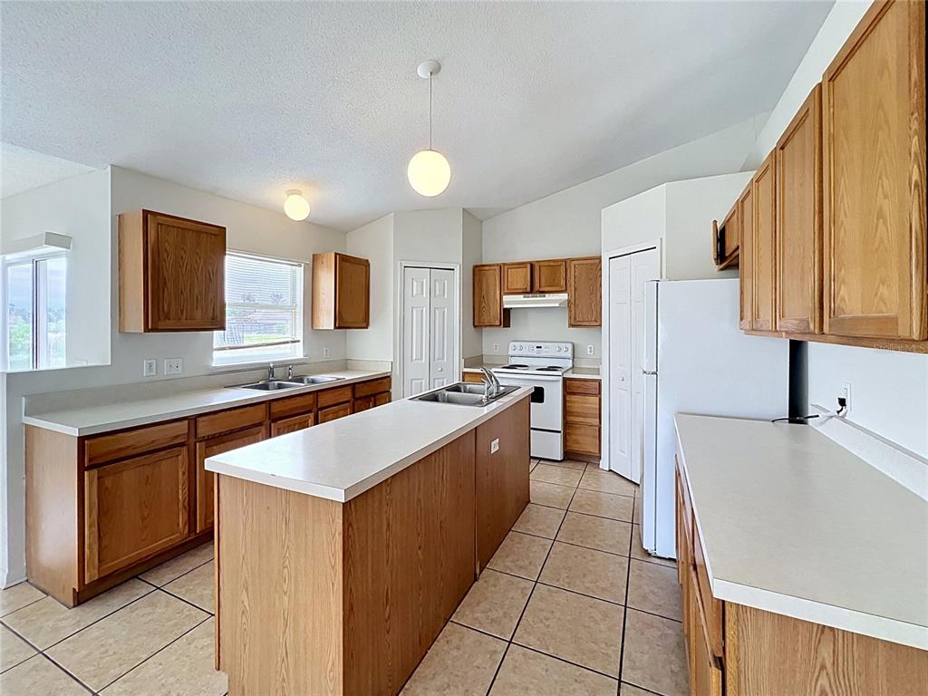 A kitchen with oak cabinets, white countertops, a center island, and tiled flooring — 6004 KALEY DRIVE, WINTER HAVEN, FL