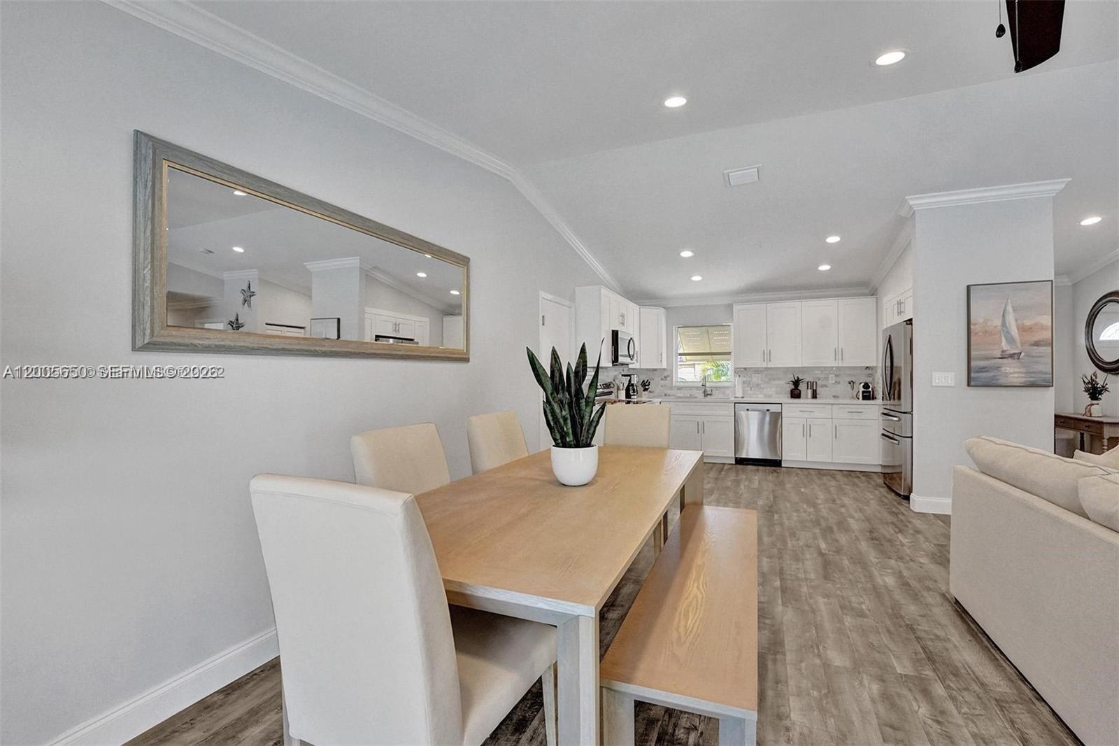 This dining area features a wooden table, bench seating, and an open kitchen with white cabinets — 6549 Sleepy Willow Way # 6549, Delray Beach FL 33484, DELRAY BEACH, FL