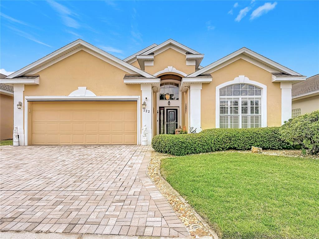 A single-story house with a beige stucco exterior, a two-car garage, and a paved driveway — 322 HIGH VISTA DRIVE, DAVENPORT, FL