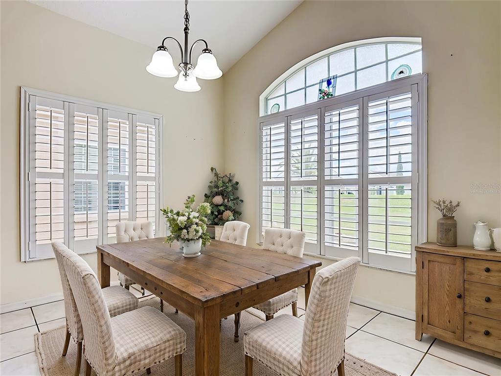 A dining room features a wooden table, upholstered chairs, plantation shutters, and a vaulted ceiling — 322 HIGH VISTA DRIVE, DAVENPORT, FL