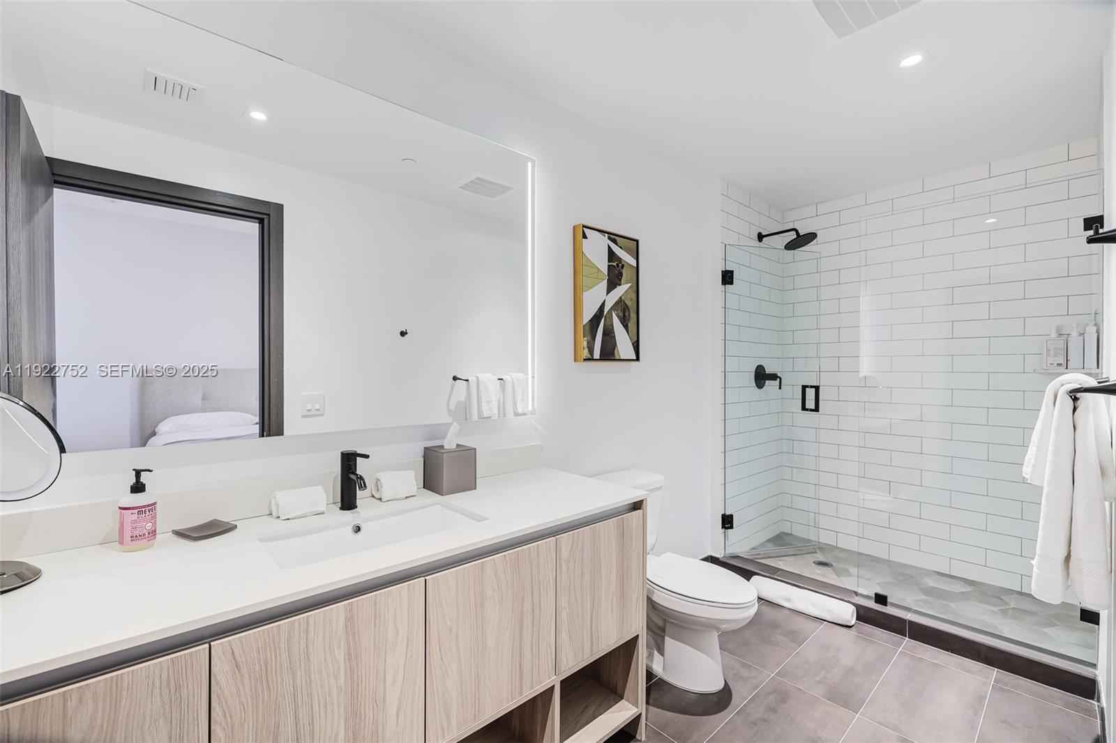 A modern bathroom features a light wood vanity, white subway tile shower, and gray flooring — 398 NE 5th St # 2319, Miami FL 33132, MIAMI, FL