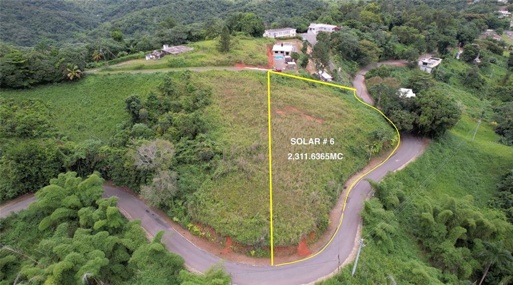 An aerial view shows a vacant, grassy plot of land outlined in yellow — SR-108 KM 11.3 CAMINO ALDEBOL SECTOR PABLO DIAZ BARRIO LEGUIZAMO, MAYAGUEZ, PR