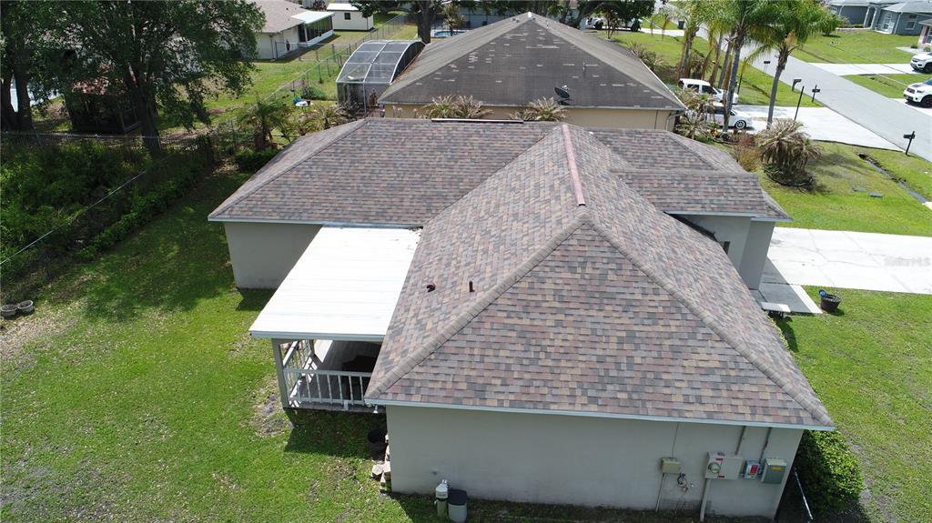 An aerial view shows the shingled roof of a house with an attached white patio cover — 782 MINK COURT, KISSIMMEE, FL
