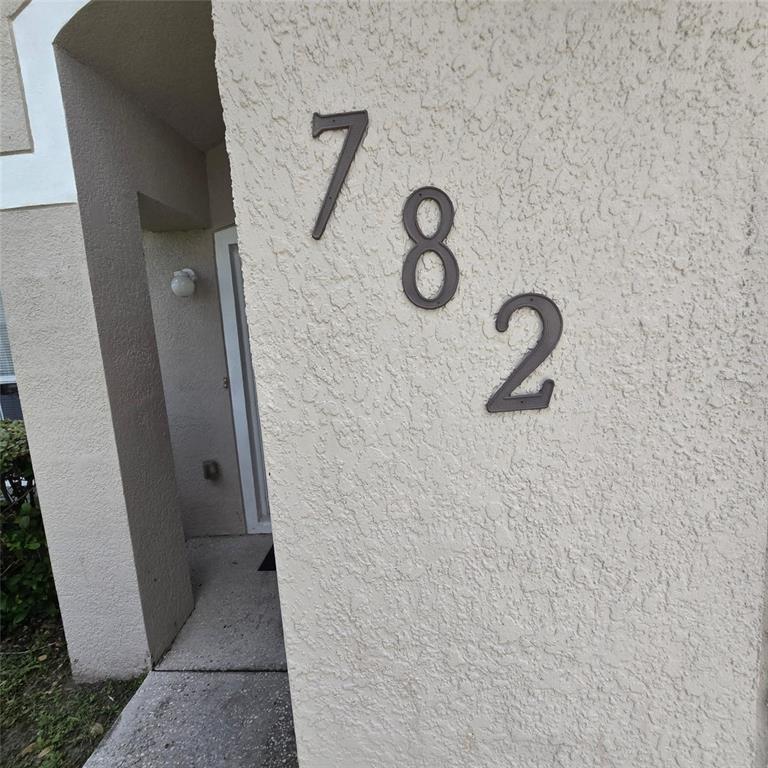 The exterior wall of a building features the house number 782 in dark metal numerals — 782 MINK COURT, KISSIMMEE, FL