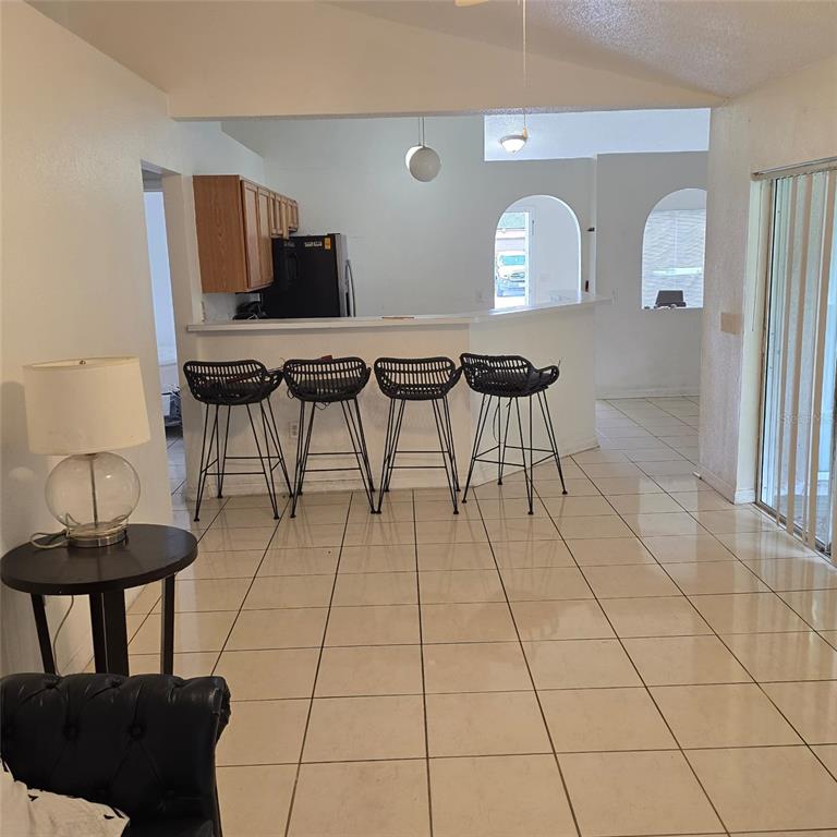 A kitchen with a breakfast bar and four stools overlooks a tiled dining area — 782 MINK COURT, KISSIMMEE, FL