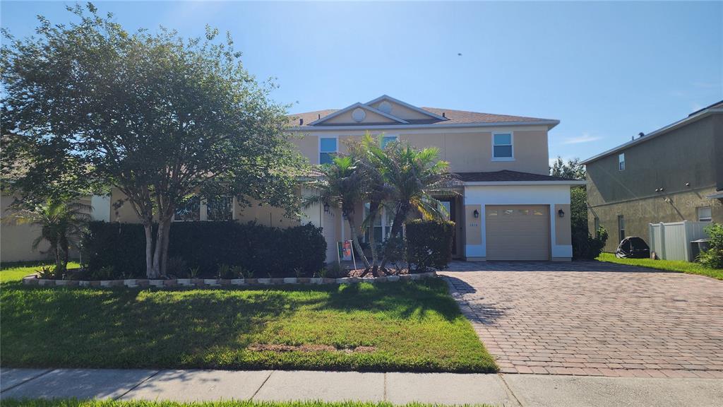 A two-story house with a paved driveway, a garage, and a large tree in front — 1915 ACACIA DRIVE, KISSIMMEE, FL