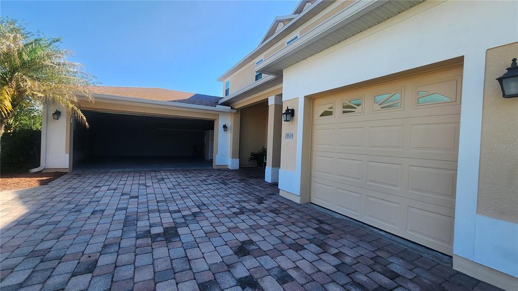 A paved driveway leads to an open garage and a closed single-car garage door — 1915 ACACIA DRIVE, KISSIMMEE, FL
